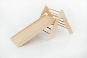 Kletterdreieck aus Holz mit einer Rutschrampe als Anbauteil, konzipiert für das Spielen von Kindern in Innenräumen und zur Förderung der motorischen Fähigkeiten.