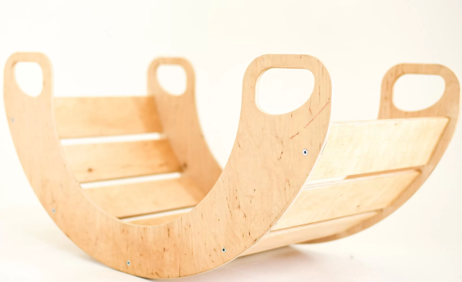 A wooden rocking toy with handles at both ends, against a plain white background.