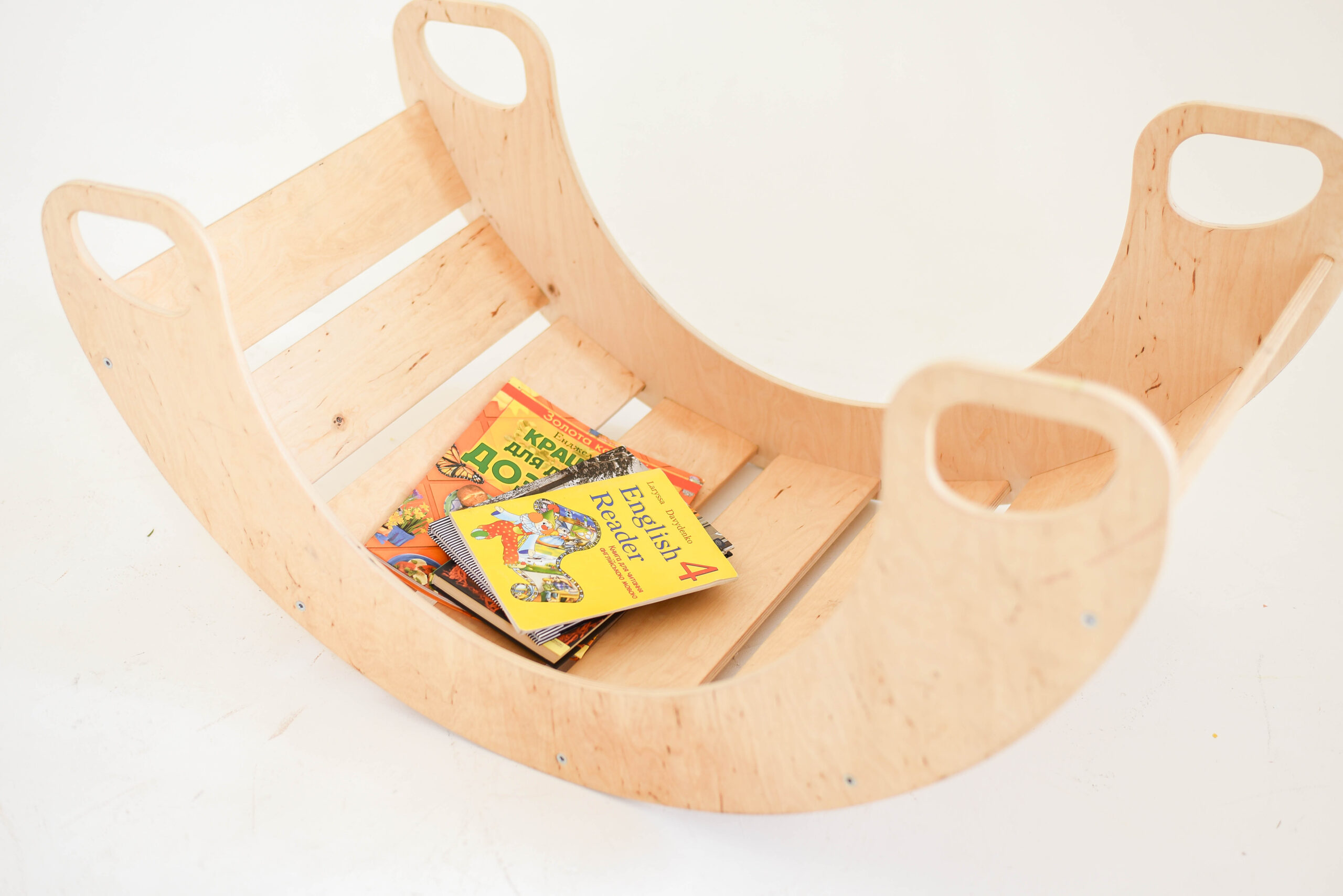 Wooden rocking toy with four picture books inside against a white background.