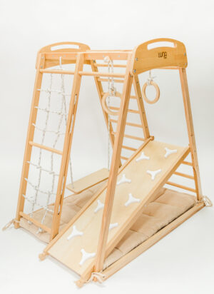 Holz-Kletterdreieck mit Rampe, Strickleiter und Ringen, aufgestellt auf einer gepolsterten Matte, zum Spielen für Kinder in Innenräumen.